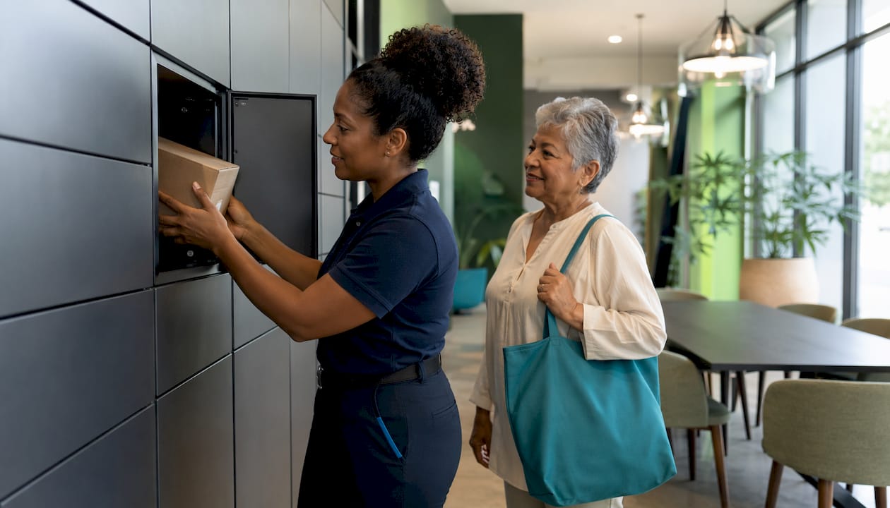 Courier placing package in indoor locker tower