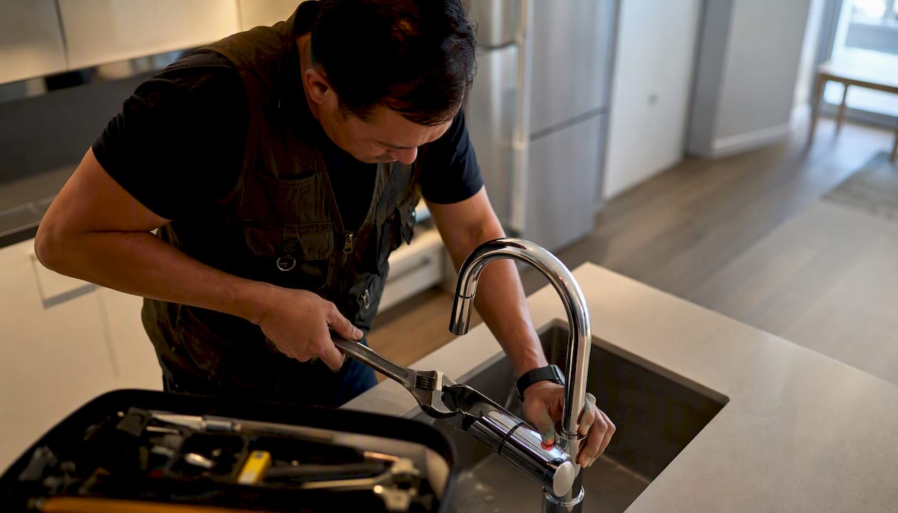 Technician adjusting faucet in apartment