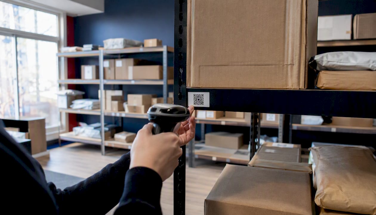 Hands scanning QR code on package shelf