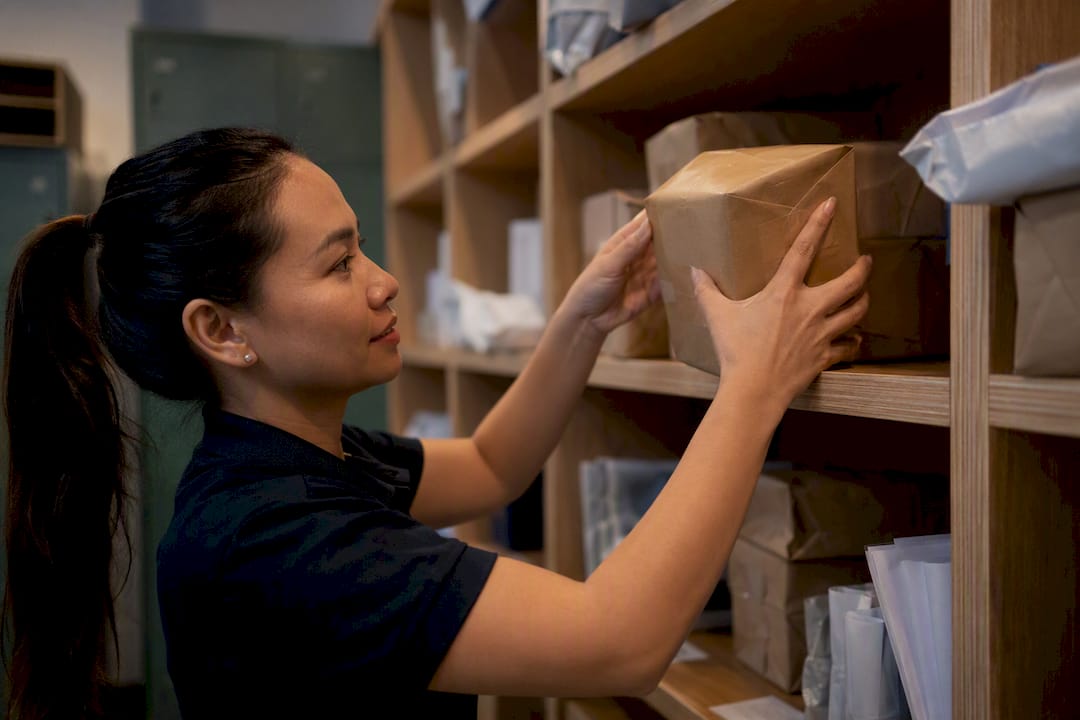 Hands placing large package on shelf in mailroom