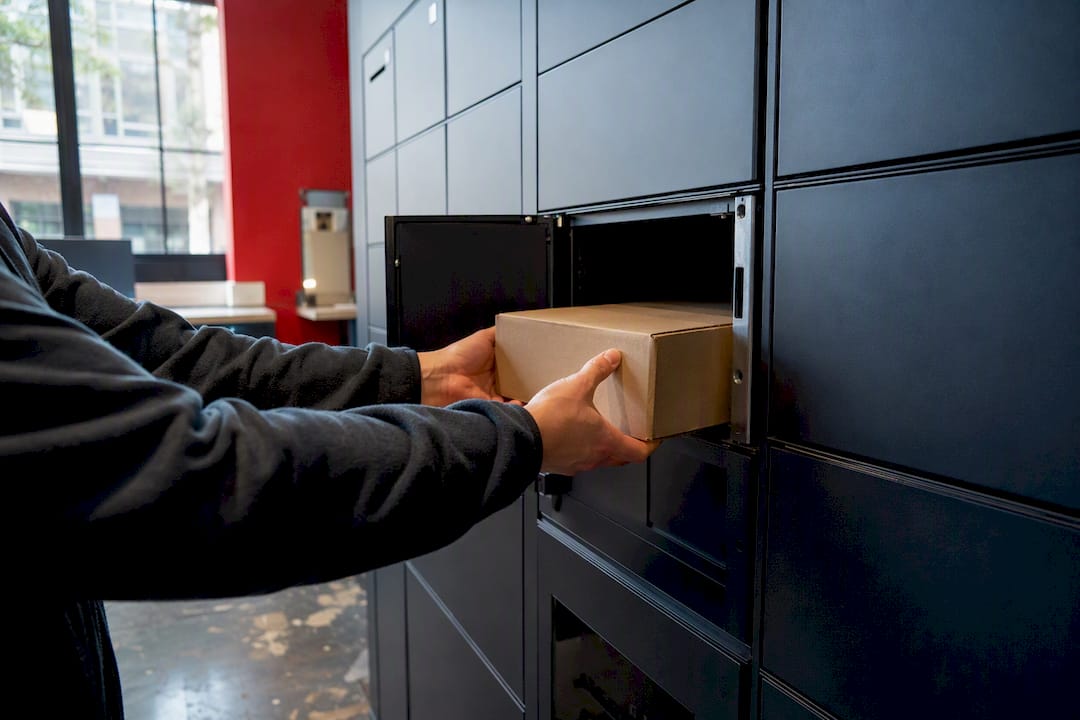 Hands placing parcel into electronic locker