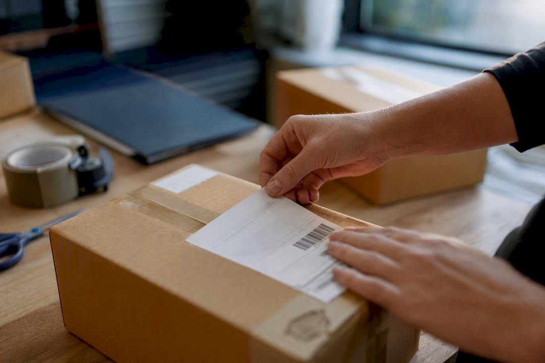 Hand applying international shipping label on parcel