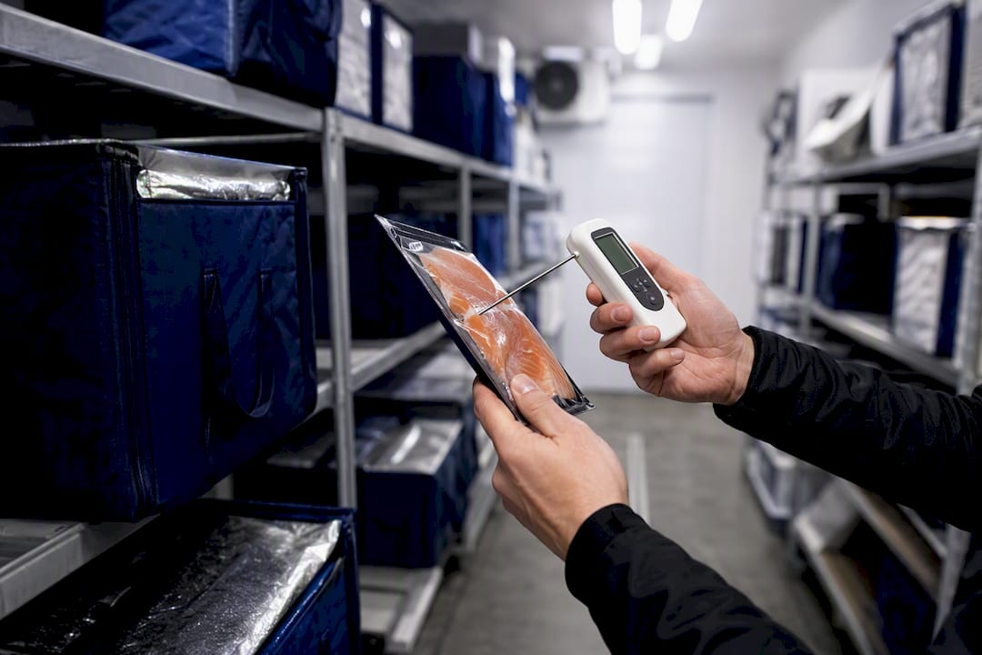 Hands checking temperature of refrigerated grocery packages