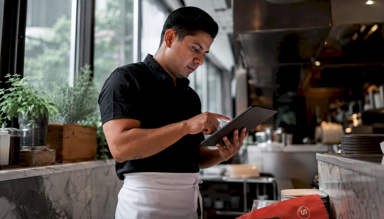 Personnel mettant à jour le menu numérique sur une tablette dans la cuisine du restaurant