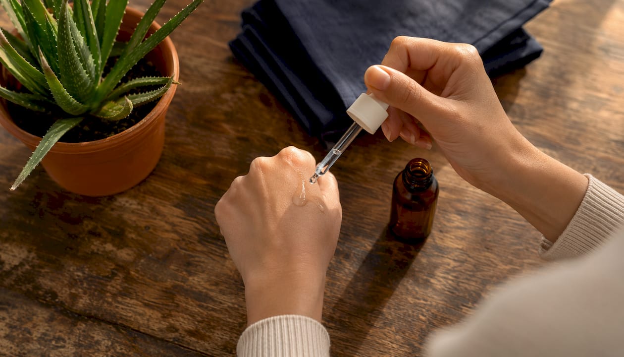 Close-up of hands applying niacinamide serum