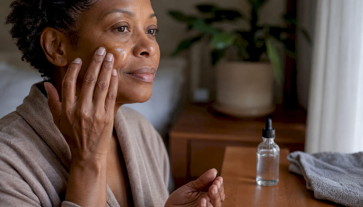 Hands applying niacinamide serum on face
