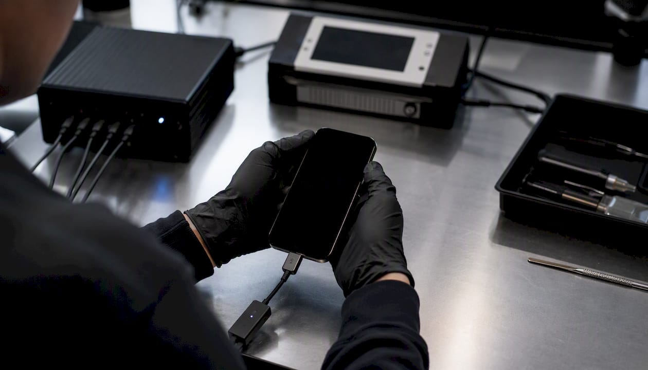 Forensics expert handling phone with tools
