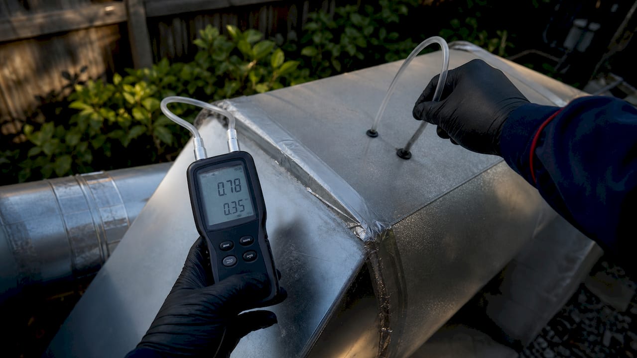 Technician measuring static pressure on duct