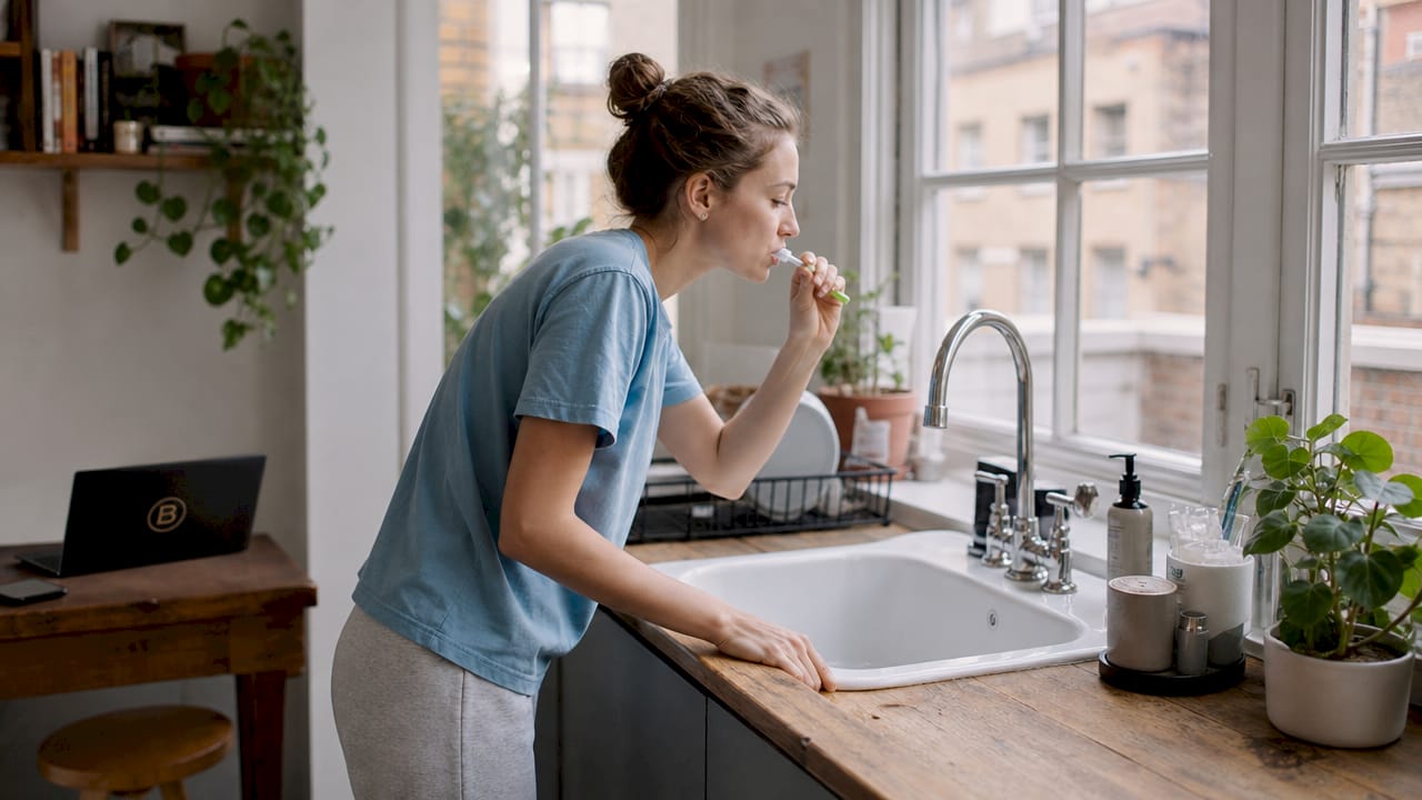 Young woman brushing teeth in bathroom, side profile