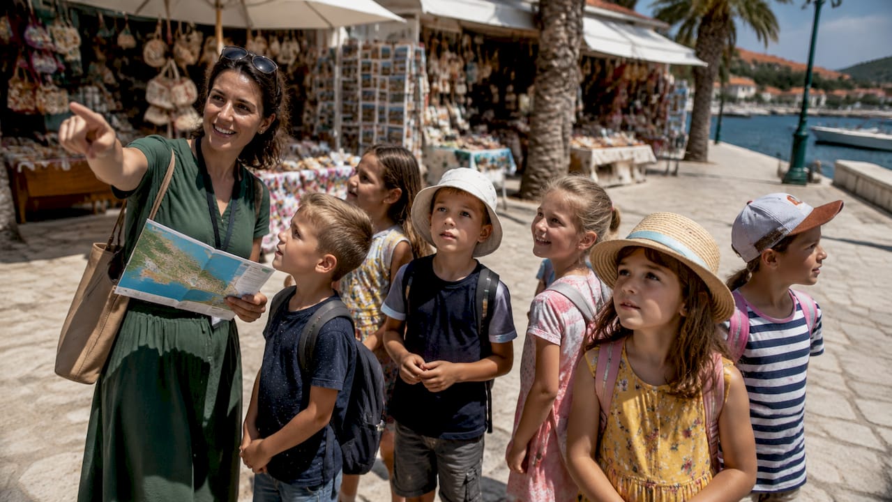 Tour guide explaining map to children outdoors