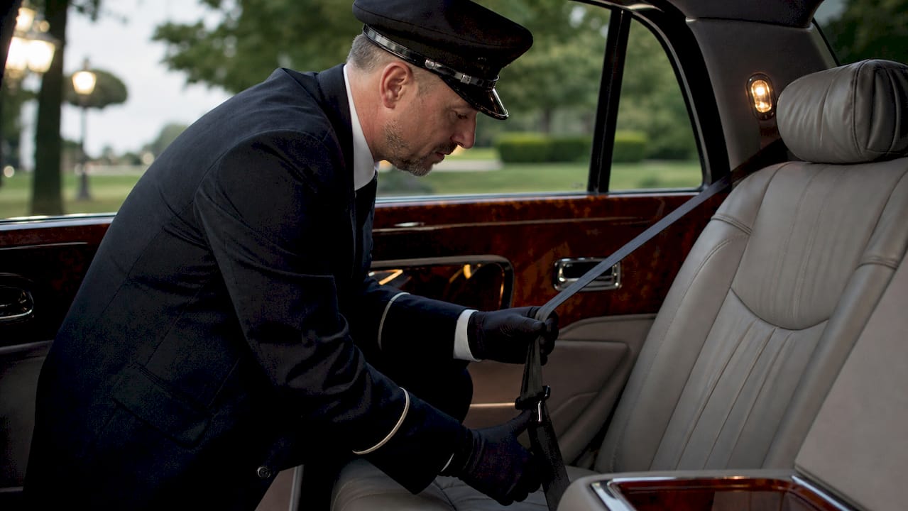 Chauffeur securing seatbelt in luxury vehicle