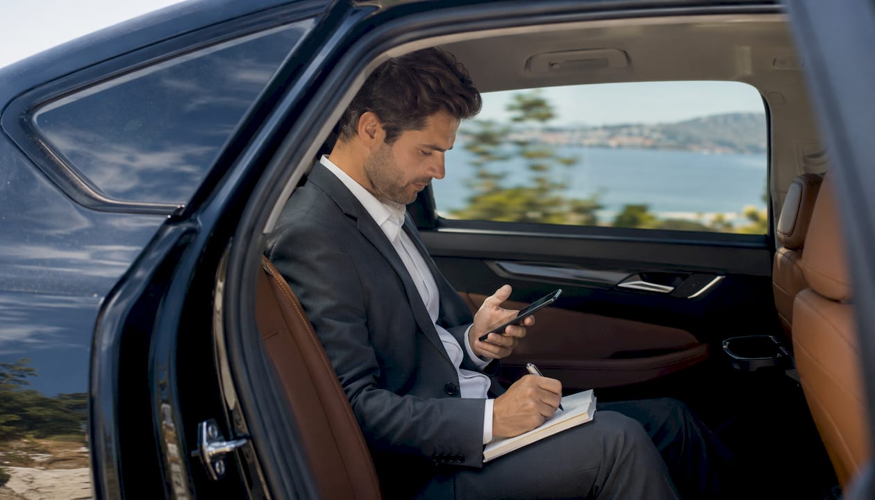 Business traveler working on tablet in luxury car