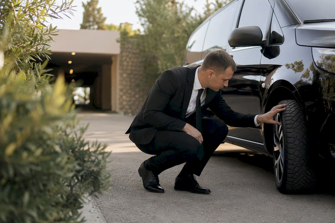 Chauffeur checking vehicle tire for safety