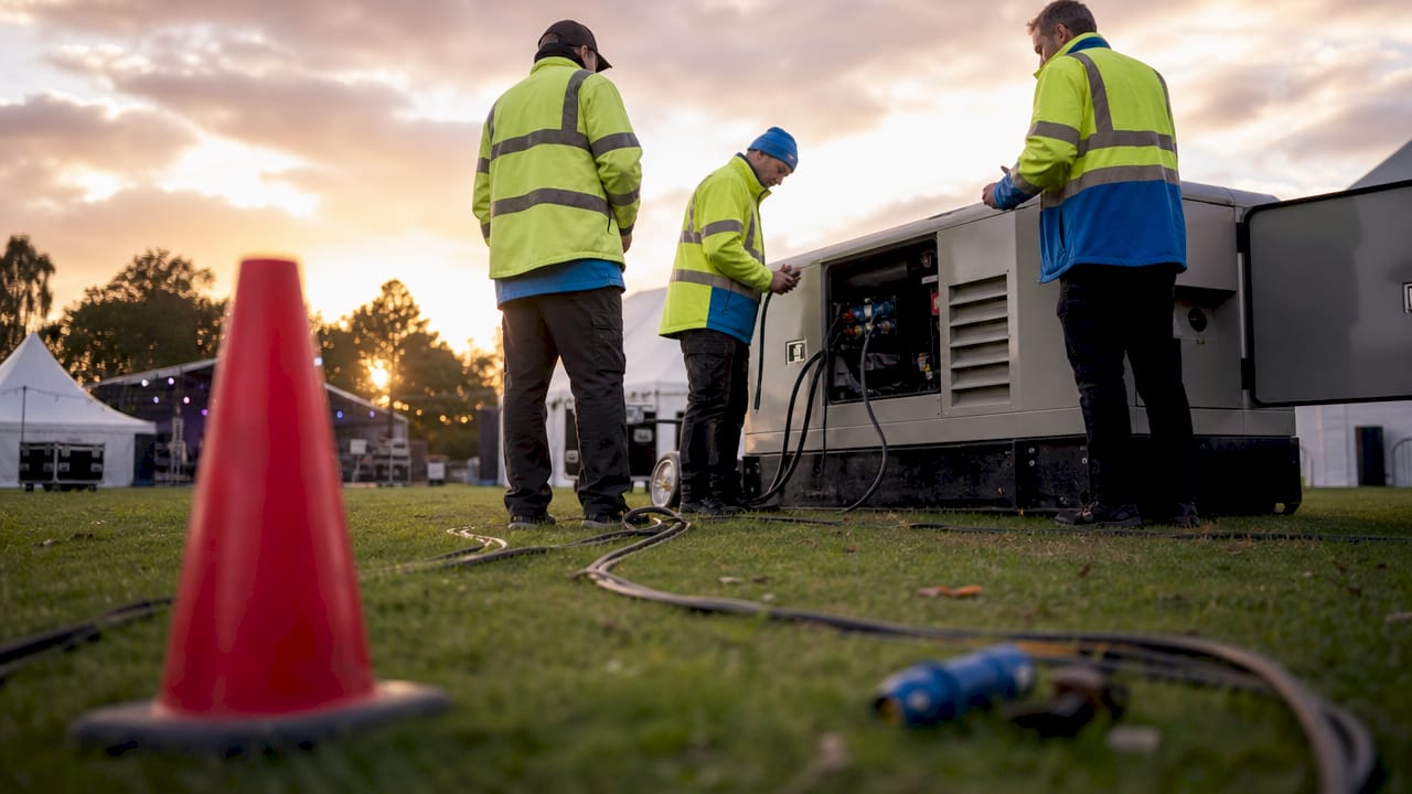 Outdoor event site with power cables and workers