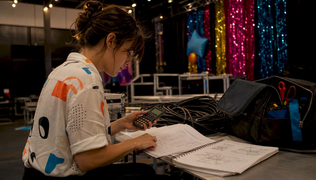 Hands calculating lighting power consumption on paper