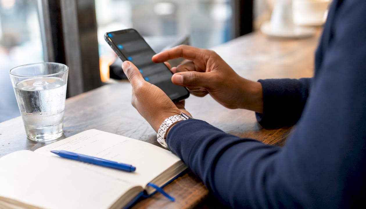 Close-up of hands using phone and notes for customer retention