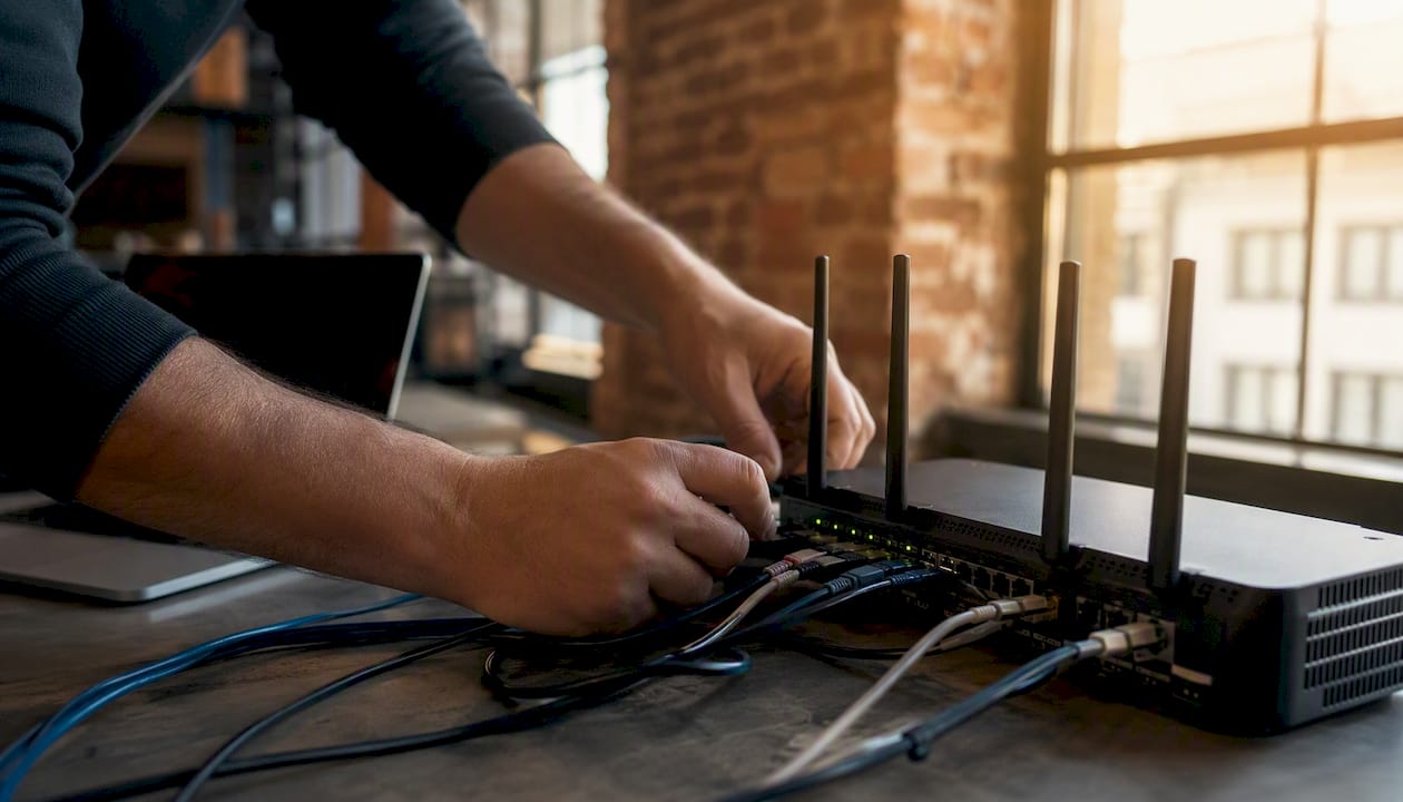 Jemand nimmt im Büro technische Anpassungen am Router vor.