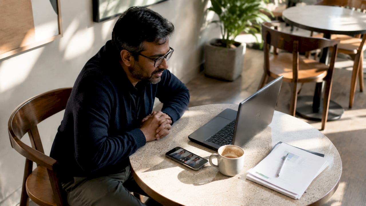 Man video calling on dual monitors in home office
