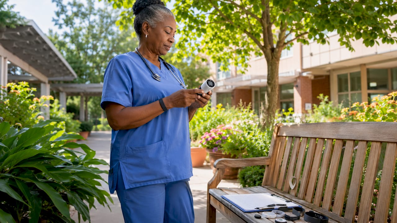 Nurse monitoring patient vitals with wireless device