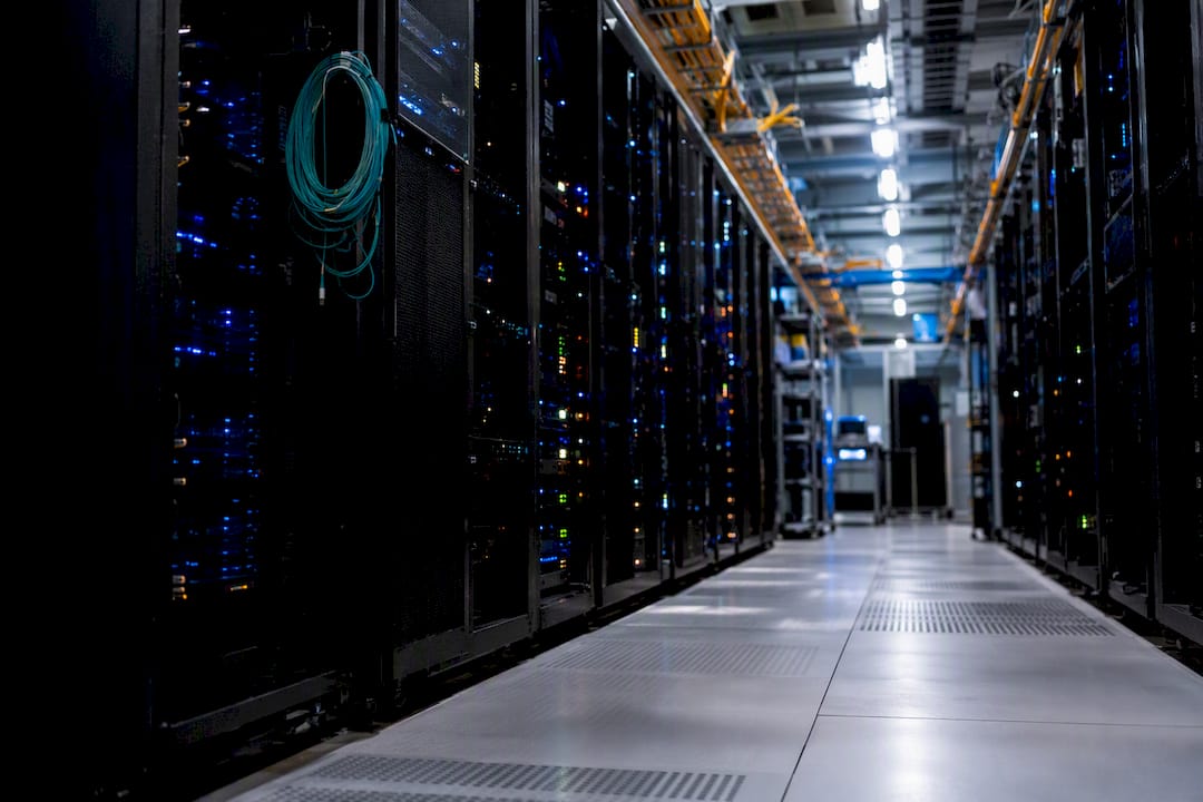 Server room aisle with illuminated racks and cables