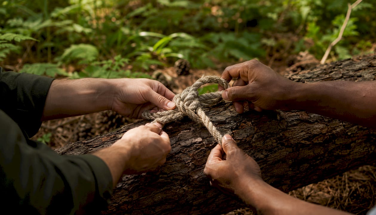Close-up hands tying knot on rope outdoors