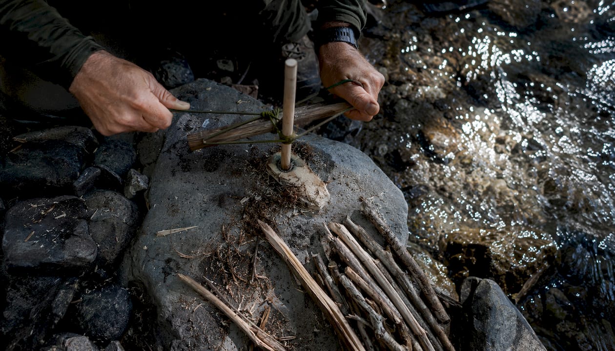 Hands preparing bow drill with paracord