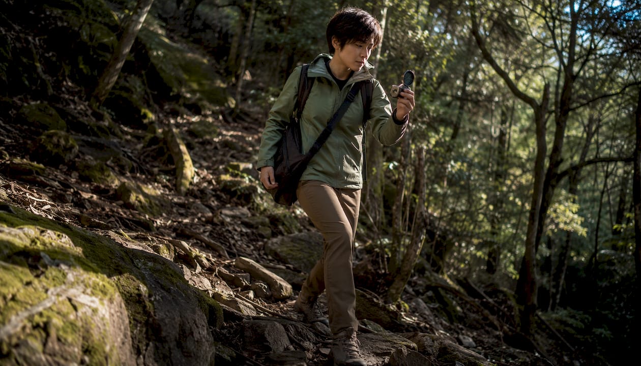 Hiker walking with compass in forest