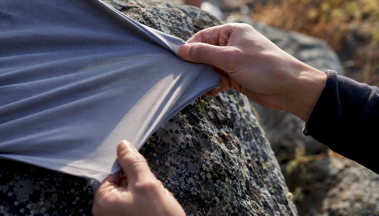 Hands stretching moisture-wicking base layer fabric