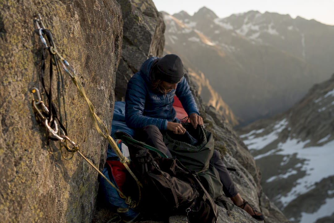 Climber secured with tether on alpine ledge bivouac