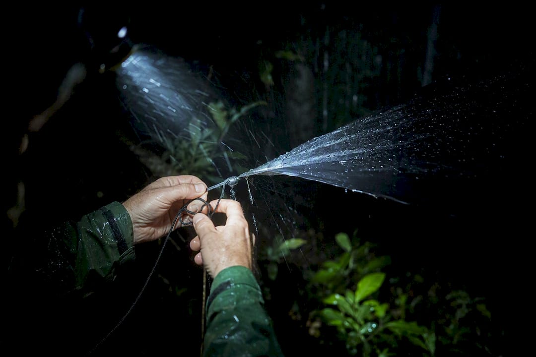 Hands adjusting bivouac tarp cordage at night