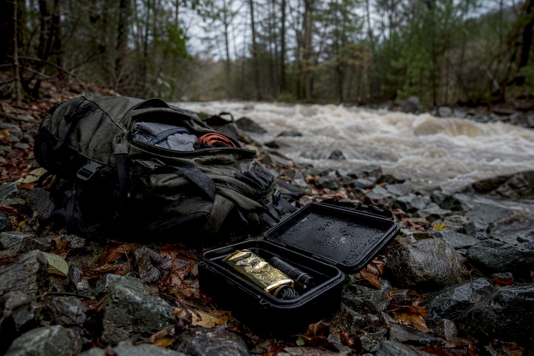 Backpack with emergency gear near rising muddy stream