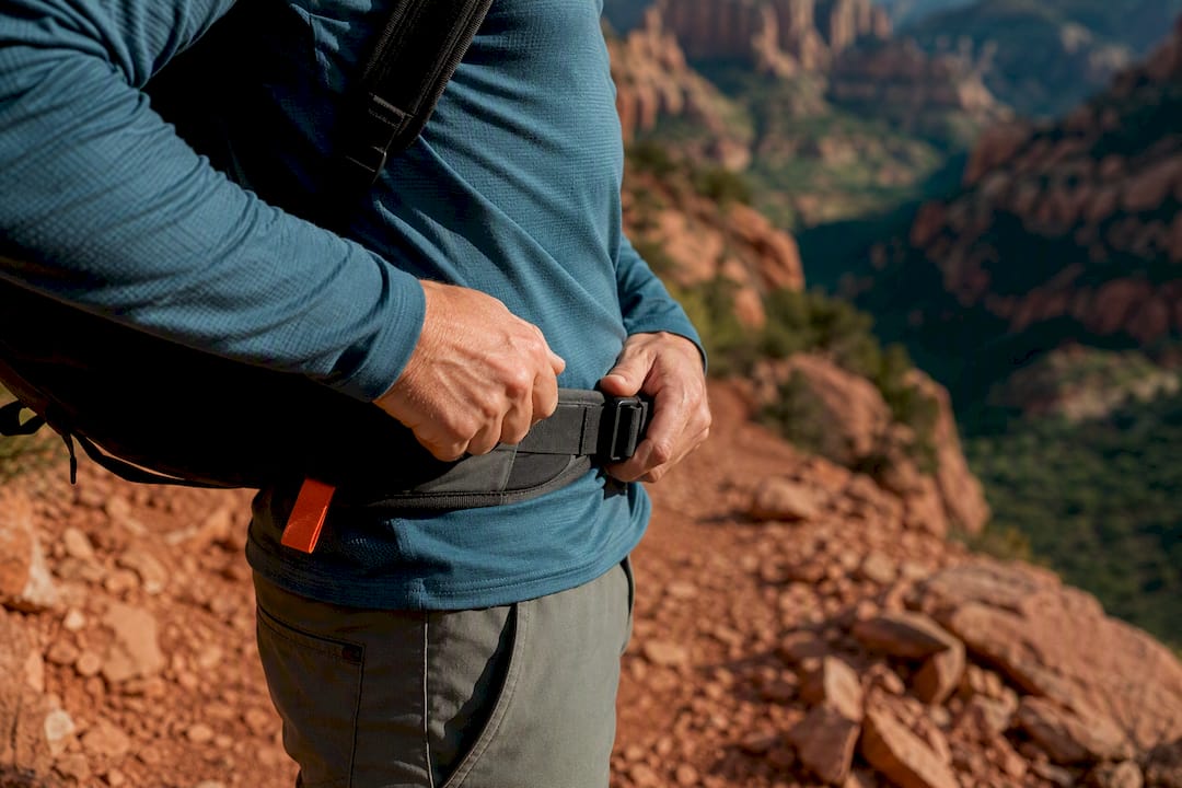 Hiker tightening backpack hipbelt on trail
