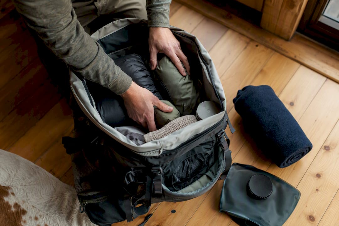 Hands placing heavy gear near pack back