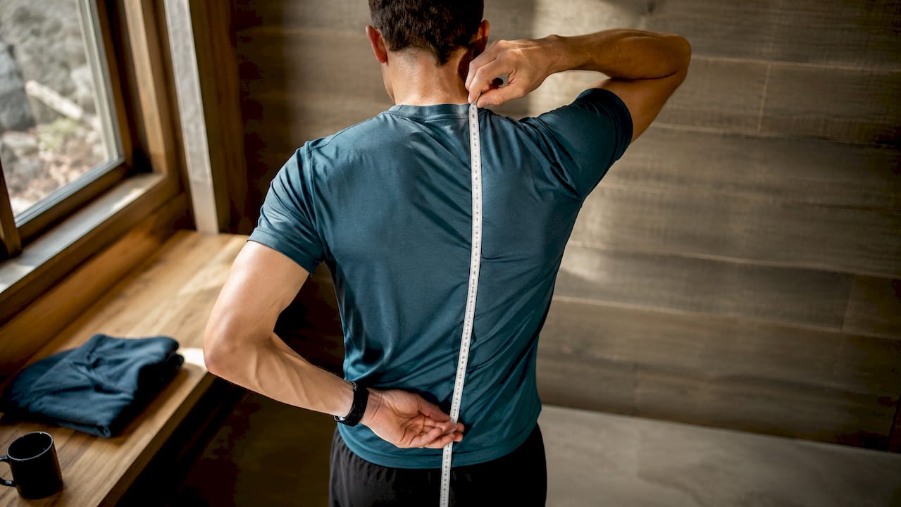 Hiker measuring torso length for pack fit