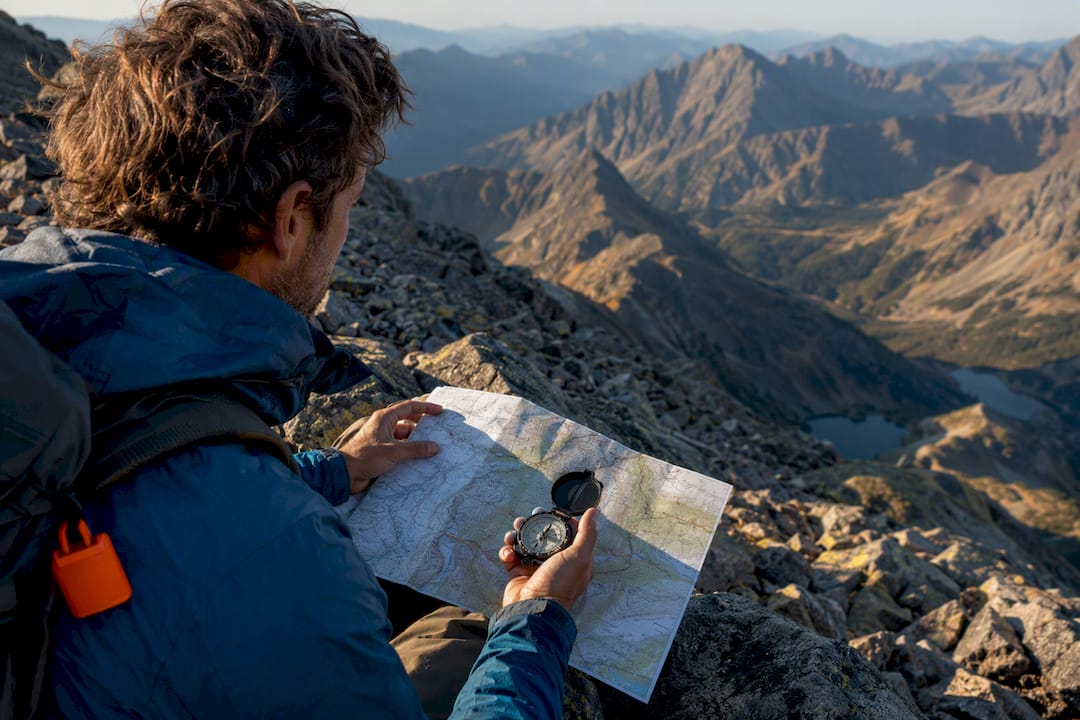 Hiker checking compass on alpine route