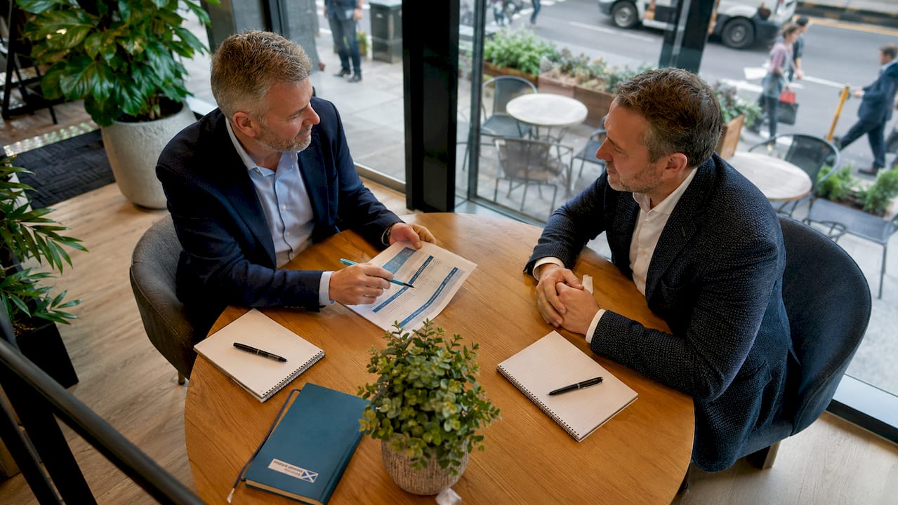 Two men discussing share option documents in office