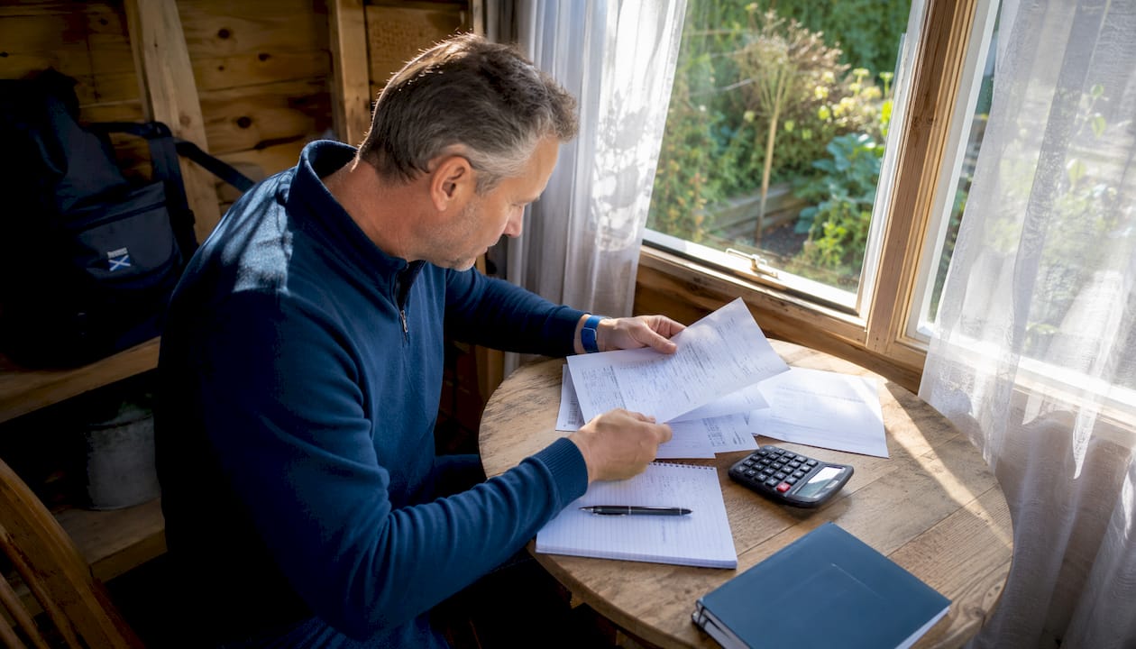 Man reviewing solicitor cost documents at kitchen table