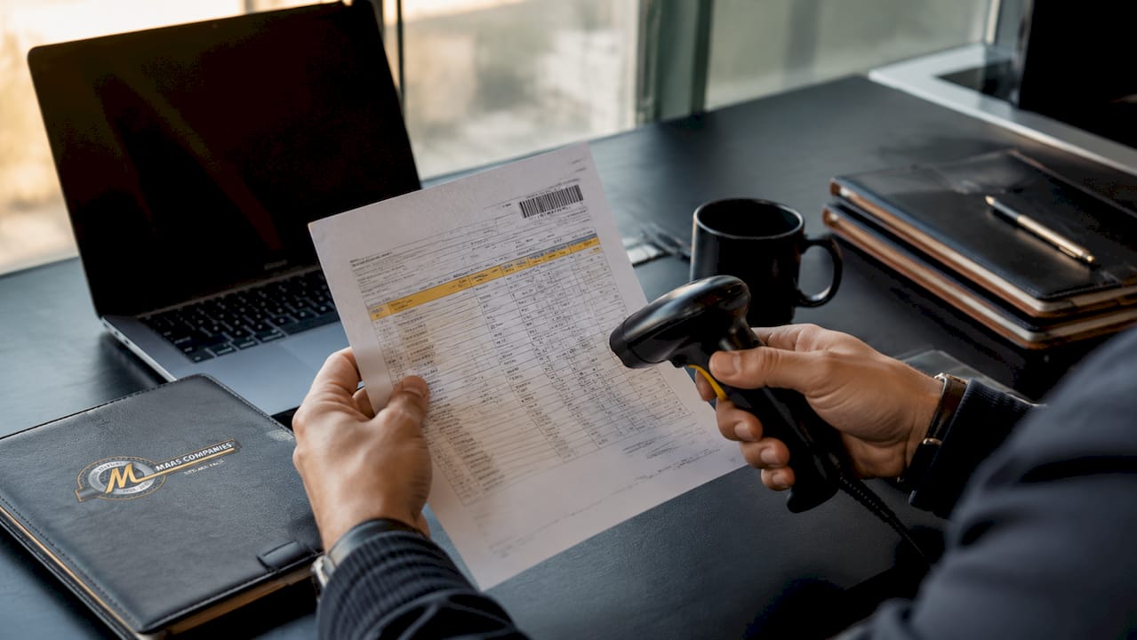 Hands reviewing asset manifest with barcode scanner
