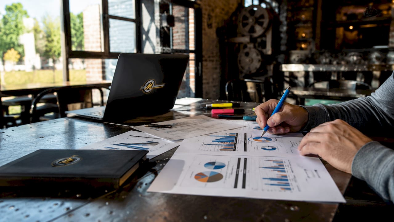 Hands pointing at industrial market charts on desk