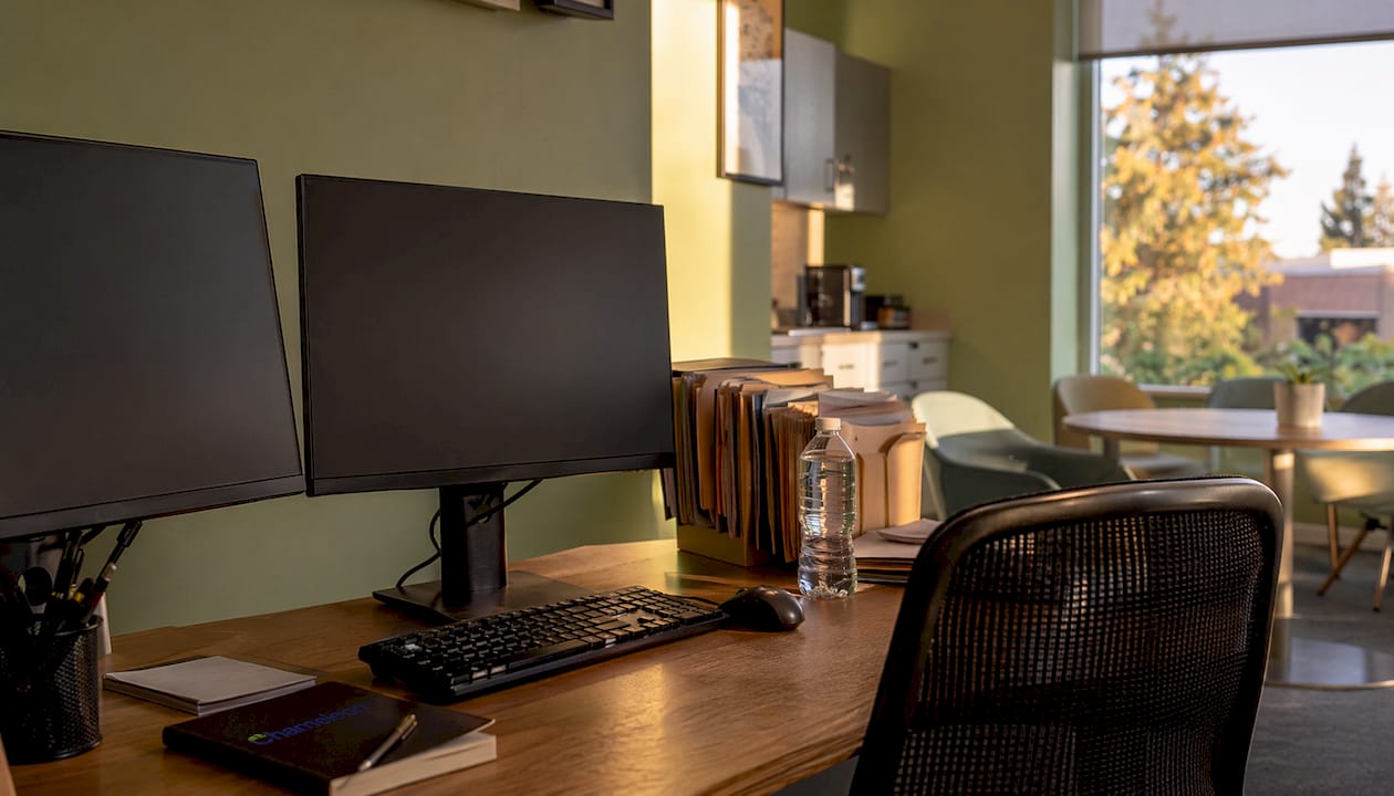 Clinician workstation with dual monitors off, hospital office