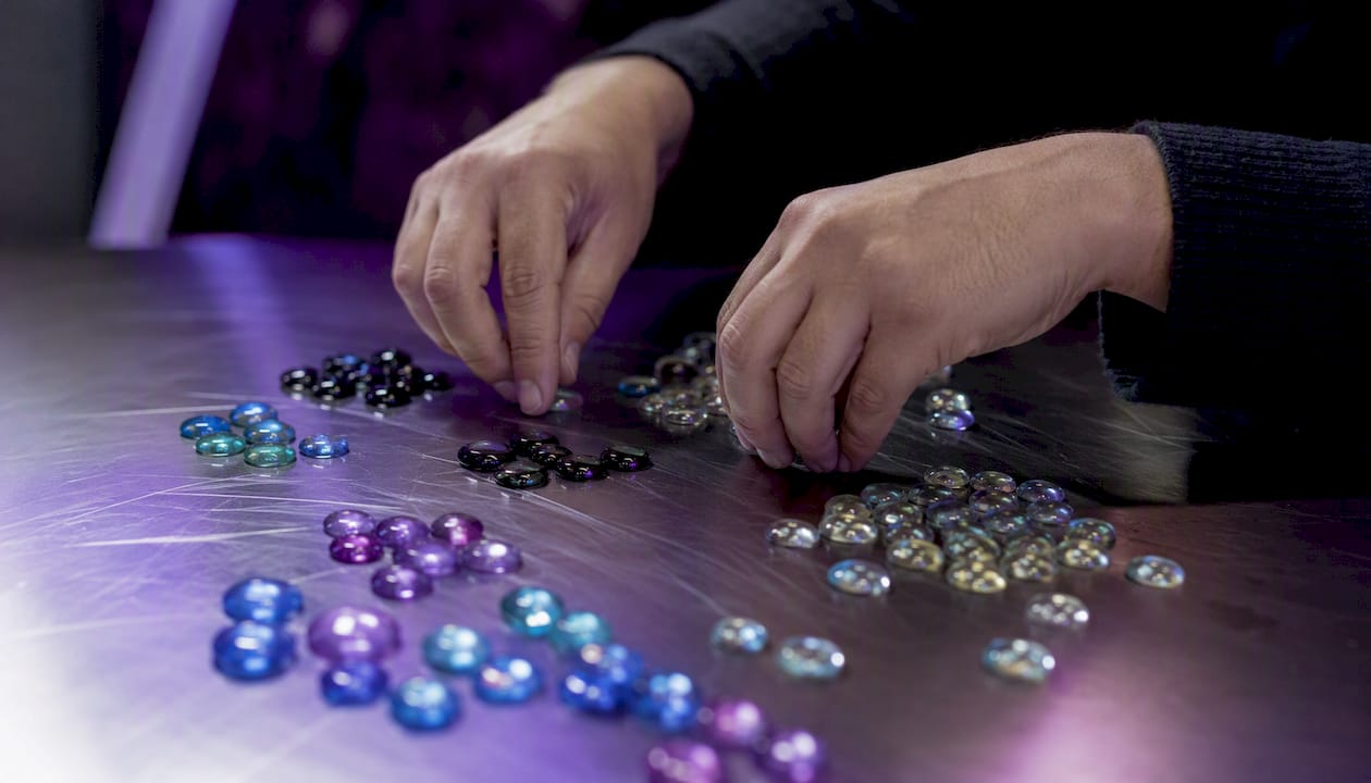 Hands sorting colored glass tiles
