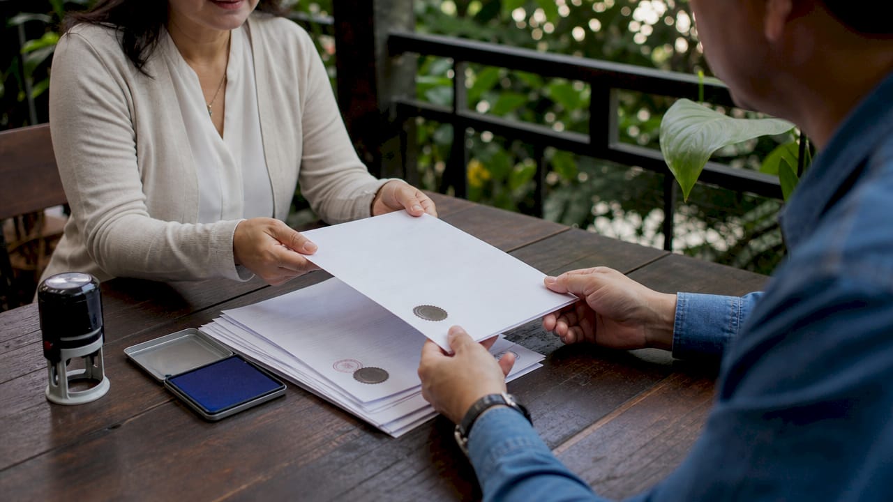 Hands exchanging notarized real estate documents