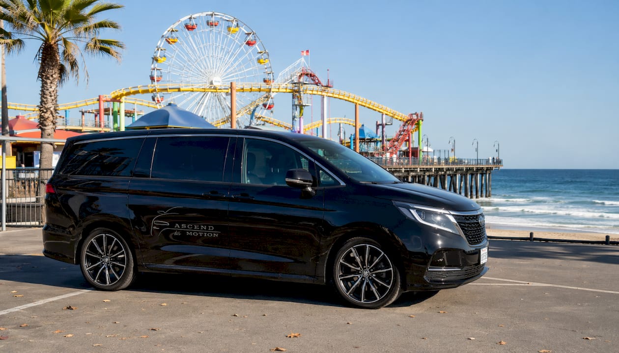 Branded black minivan near Pacific Park rides at sunset