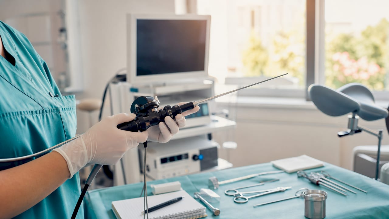 Mâinile medicului manevrează cu grijă un histeroscop modern, proaspăt sterilizat.
