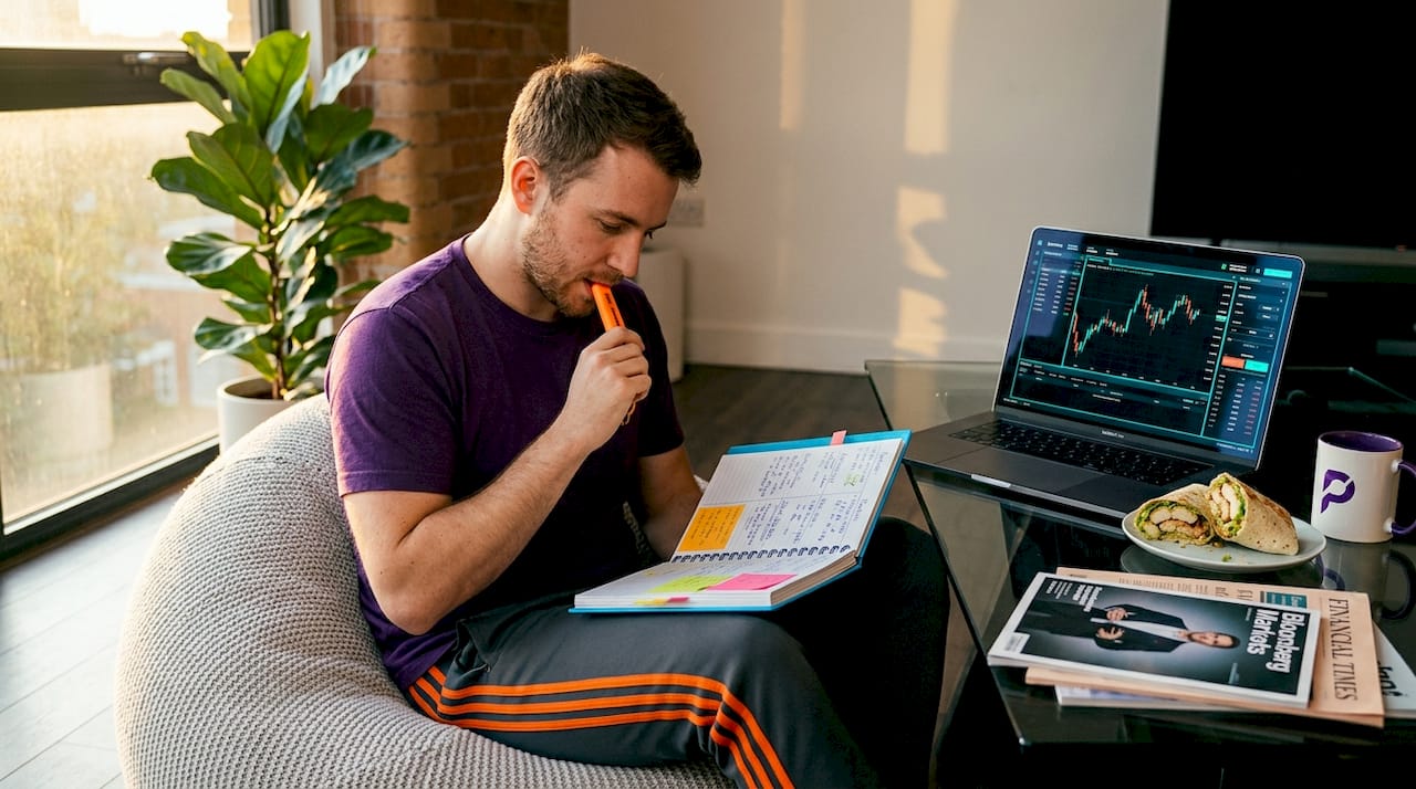 Man journaling trading results in living room