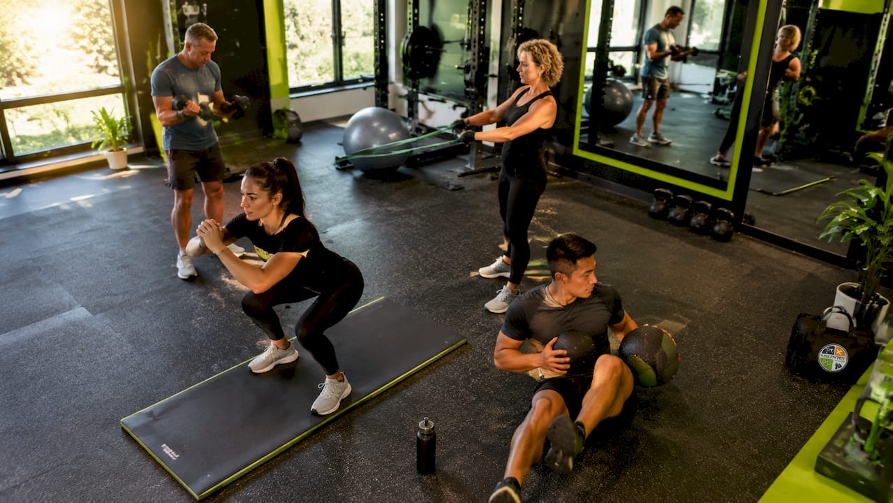 Een groep mensen van verschillende achtergronden is samen fanatiek aan het trainen in een functionele fitnessruimte.