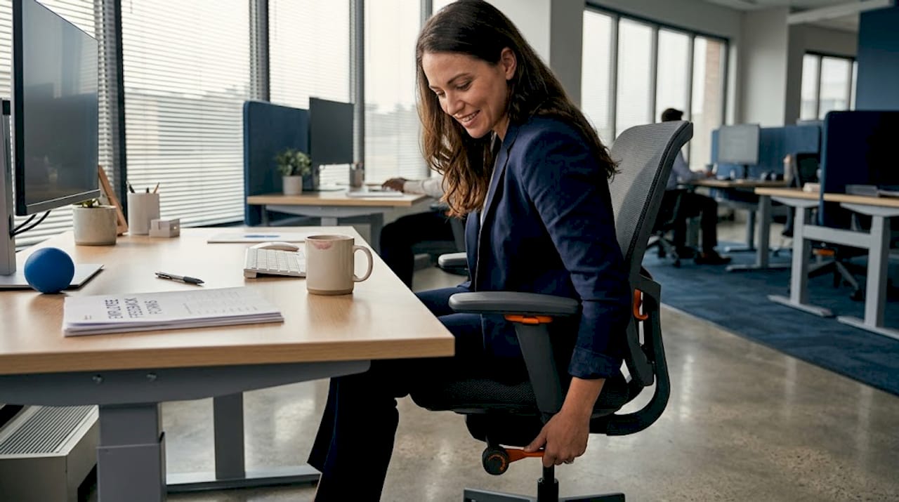 Office worker adjusting ergonomic chair at desk