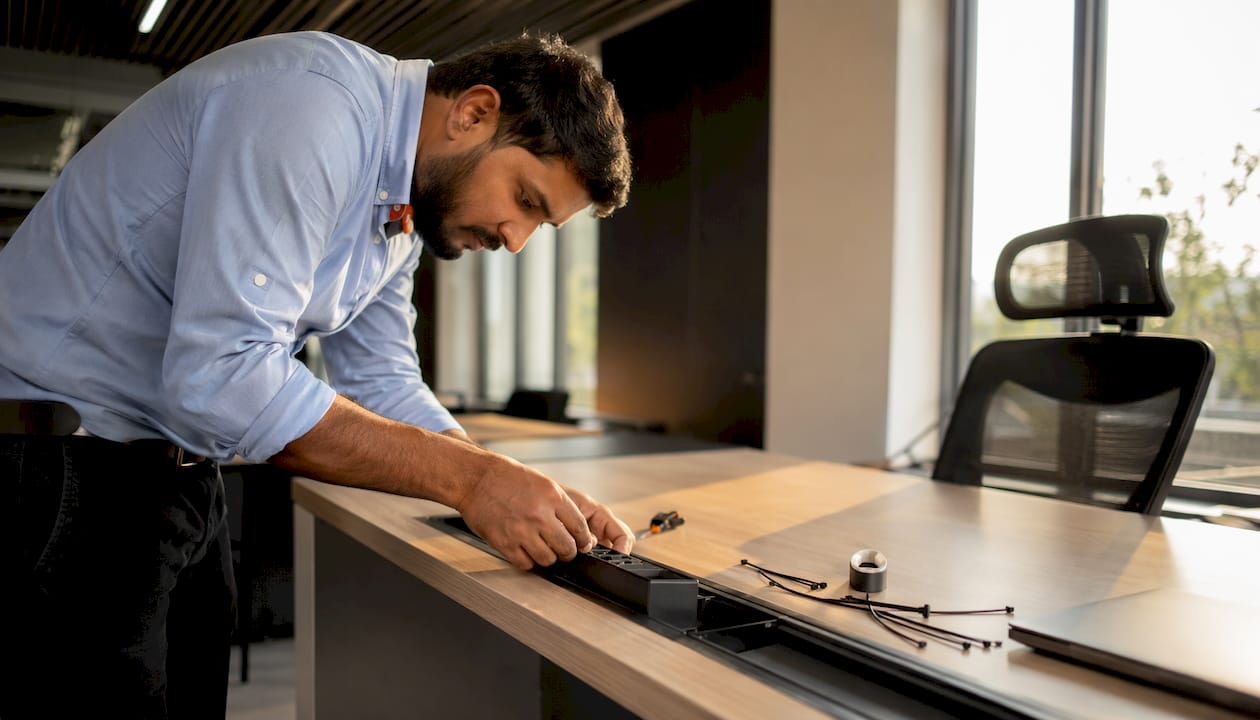 Technician fitting power modules into office desk