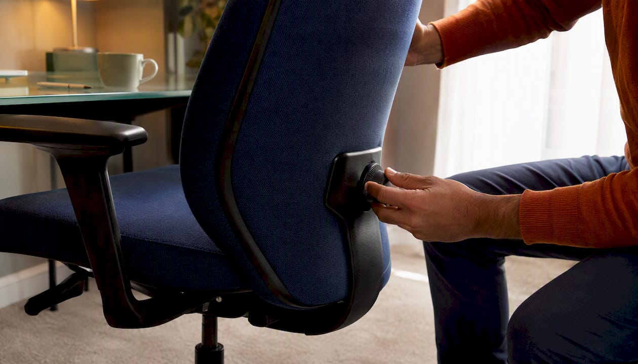 Hands adjusting lumbar support on fabric chair