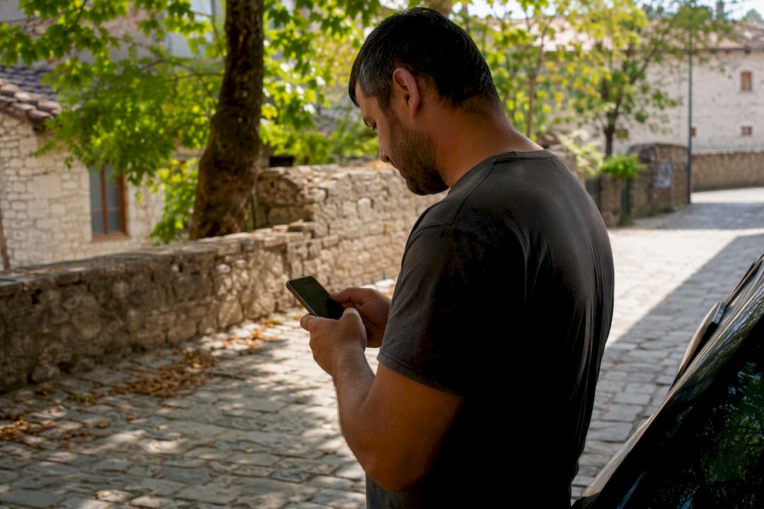 Persona che inserisce il VIN sul telefono accanto all'auto